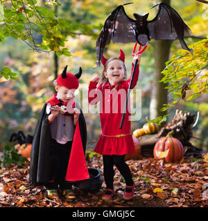 Zwei lustige Kinder tragen Teufel und Vampir Kostüm mit roten Hörnern und Trident Süßes oder Saures an Halloween. Kinder verkleidet Stockfoto