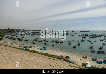 Bunte Fischerboote und Fischerdorf in der Nähe von Mui Ne, an einem sonnigen Tag. Vietnam Stockfoto