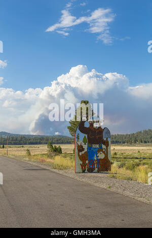 Smokey Bär Feuer Warnschild in der Sierra Nevada Kaliforniens mit der Clark ein Lauffeuer brennen im Hintergrund Stockfoto