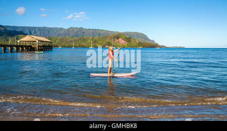 Frau Stand-up Paddeln in Hanalei Bay in der Nähe von Hanalei Pier Stockfoto