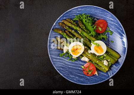 Warmer Salat von gebratenem Spargel, Feta-Käse, Tomaten und Eiern. Ansicht von oben Stockfoto