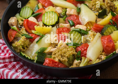Diät-Menü. Gedünstetes Gemüse mit Hähnchenfilet in Pfanne auf dem hölzernen Hintergrund. Stockfoto