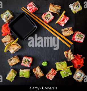 Traditionelles japanisches Essen - Sushi, Brötchen und Sauce auf einem schwarzen Hintergrund. Ansicht von oben Stockfoto