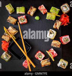 Traditionelles japanisches Essen - Sushi, Brötchen und Sauce auf einem schwarzen Hintergrund. Ansicht von oben Stockfoto