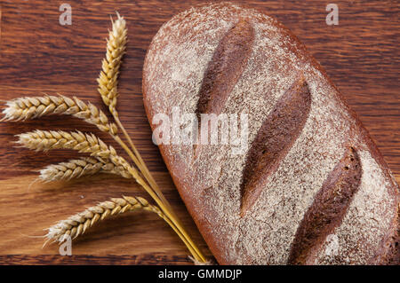 Laib Brot und Weizen über hölzerne Hintergrund Stockfoto