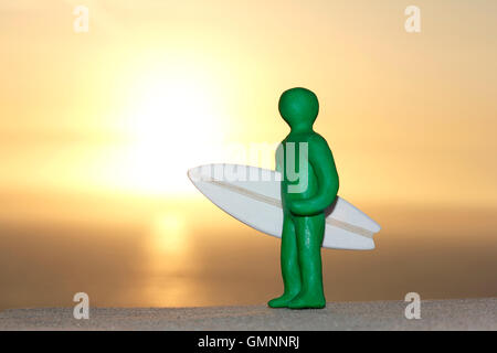 Plastilin Person und Balsa Holz Surfbrett bei Sonnenuntergang Stockfoto