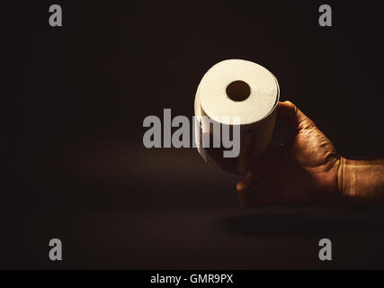 Konzeptuelle Komposition, Mannes Hand halten oder eine Rolle Toilettenpapier zu geben. Stockfoto