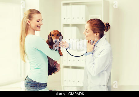 glückliche Frau mit Hund und Arzt in Tierklinik Stockfoto