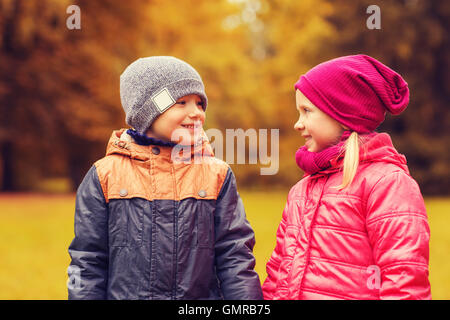 glückliche kleine Mädchen und Jungen reden im Herbst park Stockfoto