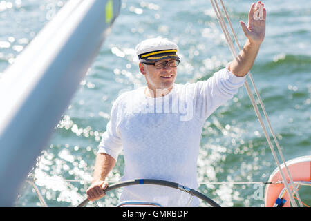 ältere Mann am Ruder auf Boot oder Yacht Segeln im Meer Stockfoto