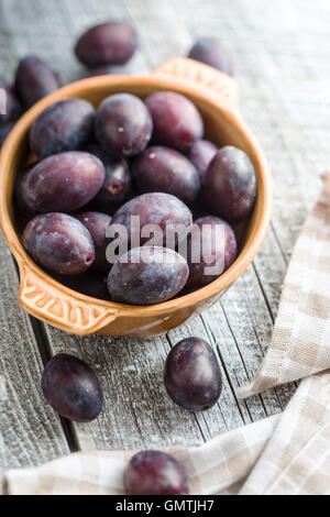 Frische Pflaumen aus Garten in Schüssel auf alten Holztisch. Stockfoto