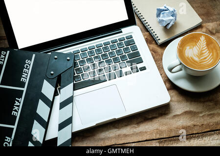 Büro-Zeug mit Film Klöppel Laptop und Kaffee Tasse Kugelschreiber Notizblock auf dem Holztisch Draufsicht shot.dark Effekt Stockfoto