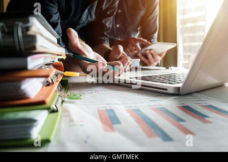 Geschäftsdokumente mit Laptop und Tablet und Graph Digitalgeschäft mit sozialen Netzwerken und zwei Kollegen diskutieren Stockfoto