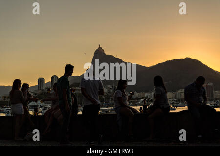 Bewohner versammeln, um den Sonnenuntergang über der Christusstatue entlang Guanabara-Bucht im Stadtteil Urca in Rio De Janeiro, Brasilien. Stockfoto