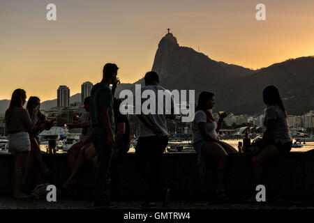 Bewohner versammeln, um den Sonnenuntergang über der Christusstatue entlang Guanabara-Bucht im Stadtteil Urca in Rio De Janeiro, Brasilien. Stockfoto