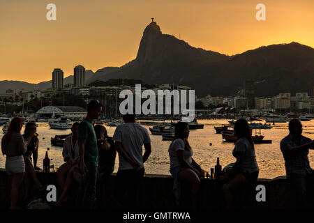 Bewohner versammeln, um den Sonnenuntergang über der Christusstatue entlang Guanabara-Bucht im Stadtteil Urca in Rio De Janeiro, Brasilien. Stockfoto