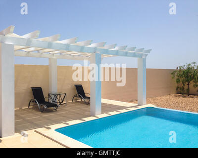 Weiße Pool-/ Pergola, Gartenlaube, die Schatten auf einer Terrasse Terrasse neben einem Schwimmbad. Mobilestock. Stockfoto