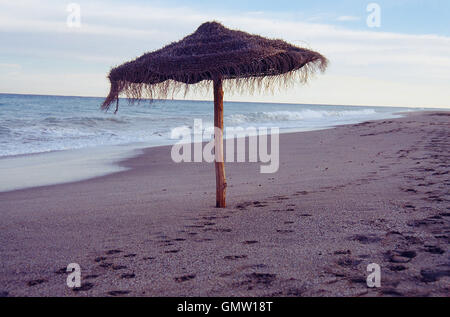 Sonnenschirm in einsamen Strand in der Abenddämmerung. Mojacar, Provinz Almeria, Andalusien, Spanien. Stockfoto