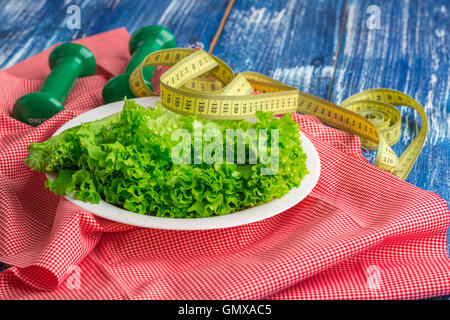 Fitness-Zusammensetzung der Salat auf weißen Teller, Gewichte und Lineal Stockfoto