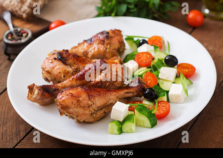 Appetitlich Ofen gebacken golden Chicken Drumsticks und griechischer Salat Stockfoto