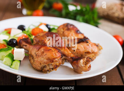 Appetitlich Ofen gebacken golden Chicken Drumsticks und griechischer Salat Stockfoto