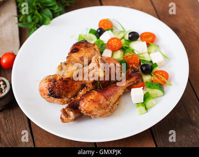 Appetitlich Ofen gebacken golden Chicken Drumsticks und griechischer Salat Stockfoto