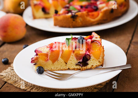 Zarte Biskuit Torte mit Pfirsichen und Heidelbeeren. Stockfoto