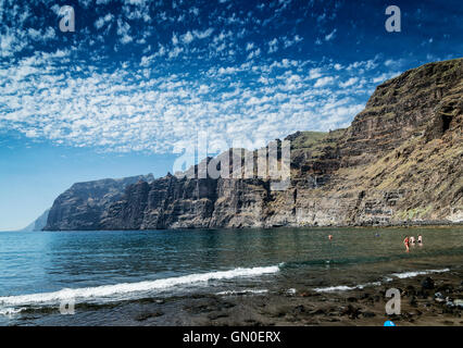 Touristen in Los Gigantes vulkanischen schwarzen Sandstrand von berühmten natürlichen Klippen Wahrzeichen im Süden von Teneriffa Baden Insel Spanien Stockfoto