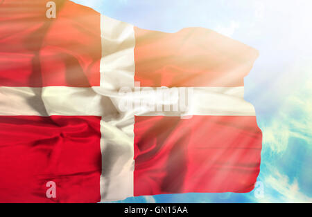 Dänemark, die wehende Flagge gegen blauen Himmel mit Sonnenstrahlen Stockfoto