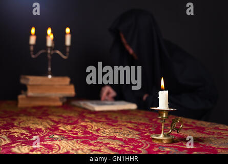 Kerze auf dem Hintergrund des Mönchs lesen Stockfoto