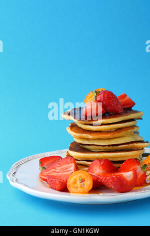 Warme Pfannkuchen mit frischen Früchten vor blauem Hintergrund Essen Nahaufnahme Stockfoto