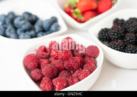 on a white background in white bowls of fresh, juicy wild berries blueberries raspberries strawberries and blackberries, delicio Stockfoto