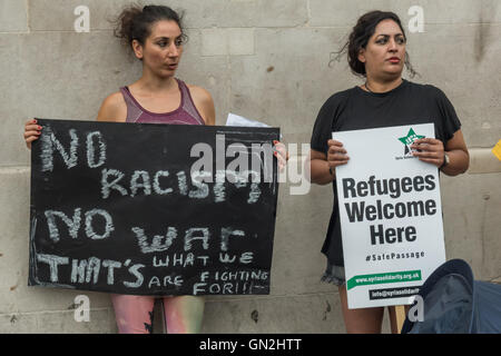 London, UK. 27. August 2016. Frauen halten ein Poster und Plakat bei einer Demonstration von Help4Refugee Kindern, Syrien Solidaritätskampagne, Calais Aktion & RS21 auf dem Trafalgar Square Flüchtlinge gefordert, wie Menschen behandelt werden und durch die Genfer Flüchtlingskonvention und späteren Vereinbarungen festgelegten Rechte gegeben werden genannt. Sie sagen, Behandlung von Flüchtlingen in unmenschlicher Weise sehen wir derzeit nicht akzeptabel ist - kein Mensch ist illegal - und sie sollten die gleichen Menschenrechte wie unsere eigenen und nicht Asyl, verweigert oder von der Polizei schikaniert und trieben in schockierend, menschenunwürdigen Bedingungen wie "Dschungelcamp" in Calais. Stockfoto