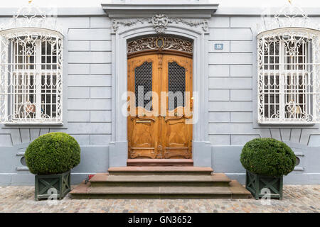 Vorderansicht des eine elegant geschnitzten leichte braune Holztür mit verzierten grauen Rahmen und Wand. Stockfoto