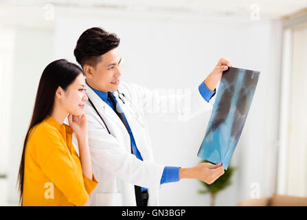 junger Arzt, Patientin Röntgenfilm betrachten Stockfoto