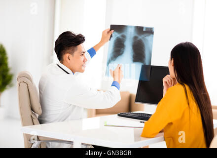 junger Arzt, Patientin Röntgenfilm betrachten Stockfoto