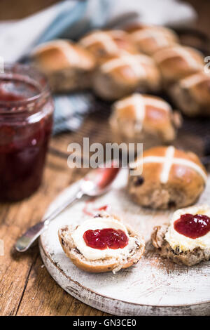 Nachmittags-Tee, heiße Kreuz Brötchen mit Erdbeer-Marmelade und Clotted cream Stockfoto