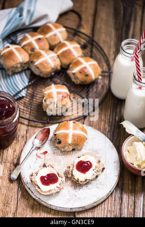 Nachmittags-Tee, heiße Kreuz Brötchen mit Erdbeer-Marmelade und Clotted cream Stockfoto