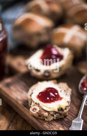 englische Hot Cross Bun mit Clotted Cream und Marmelade Stockfoto