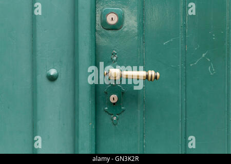 Eine grün bemalte Holztür mit einem Bronze Türgriff und zwei Schlüssellöcher. Stockfoto