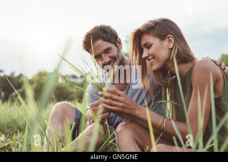 Paar in einem Feld Gras sitzen. Mann und Frau gemeinsam mit Wild grass in der hand. Stockfoto