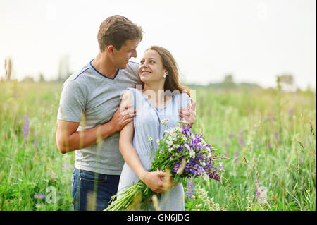 junges Paar in Liebe zu Fuß auf der Sommerwiese Stockfoto