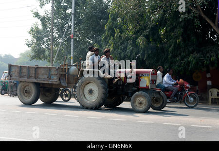 Ein Traktor mit einem leeren Anhänger, getrieben von den einheimischen Bauern an einer belebten Hauptstraße in Agra, Uttar Pradesh.India Stockfoto