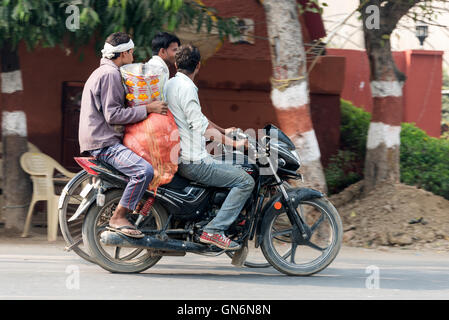 Zwei Fahrer mit einem großen Sack auf einem Motorrad auf der Hauptstraße in Agra, Uttar Pradesh, Indien, Stockfoto