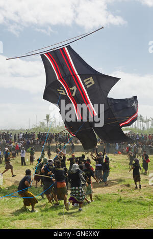 BALI, Indonesien - 15 Juli 2012: Gruppe von unbekannten Männern Linien halten und versuchen, gefährliche Landung großen Drachen zu fangen Stockfoto