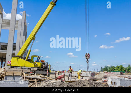 Mobiler Kran arbeitet daran, große Montagehalle. Platzieren den Dachstuhl auf den Aufbau von Skelett. Stockfoto