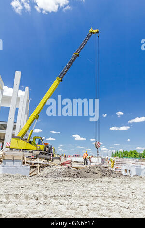 Mobiler Kran arbeitet daran, große Montagehalle. Platzieren den Dachstuhl auf den Aufbau von Skelett. Stockfoto