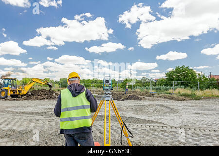 Vermesser Ingenieur misst Ebene auf Baustelle. Vermesser gewährleisten präzise Messungen vor großen baugewerblicher Unternehmen Stockfoto