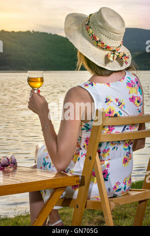 Frau mit einem Glas Wein am See Stockfoto