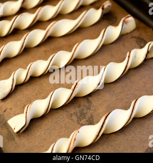 Hausgemachte rohe Schokolade Blätterteig Wendungen frisch zubereitet zum Backen im Tray auf braune Trägerpapier Grissini Stockfoto